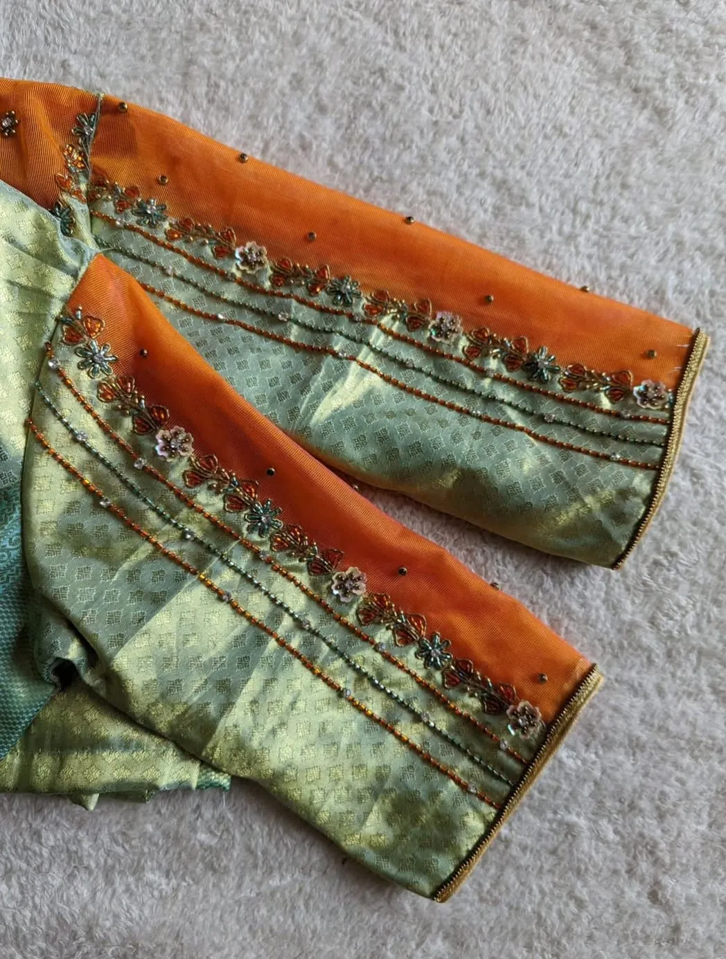 Sage Green Brocade Silk Saree Blouse with Contrast Orange Net Illusion V-Neck & Hand Beaded Sleeves